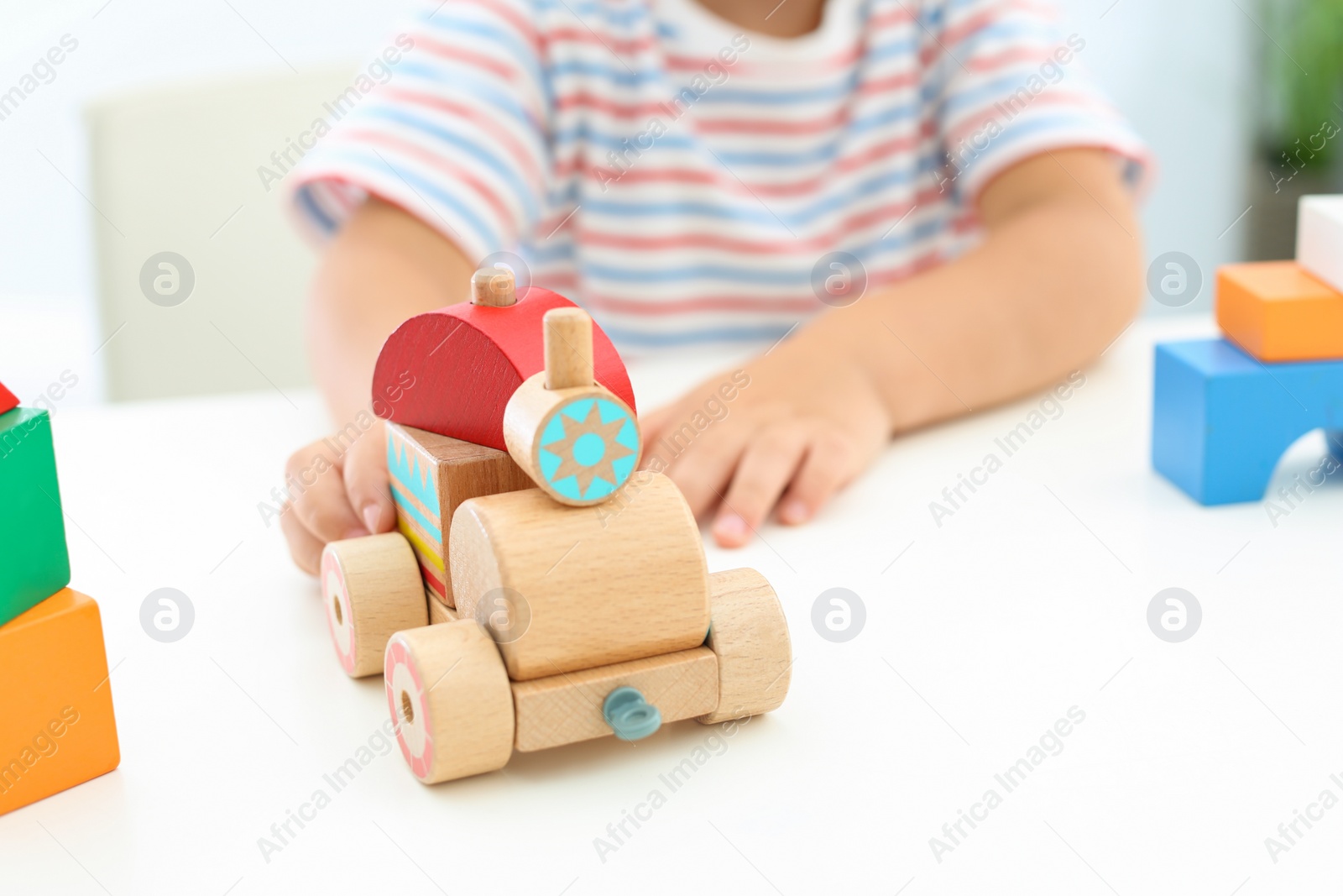 Photo of Little boy playing with toy at white table, closeup