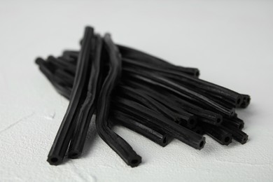 Photo of Tasty black liquorice candies on white table, closeup