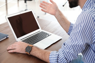 Man using video chat on laptop in home office, closeup. Space for text