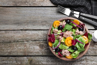 Photo of Bowl of delicious salad with canned tuna and vegetables served on wooden table, flat lay. Space for text