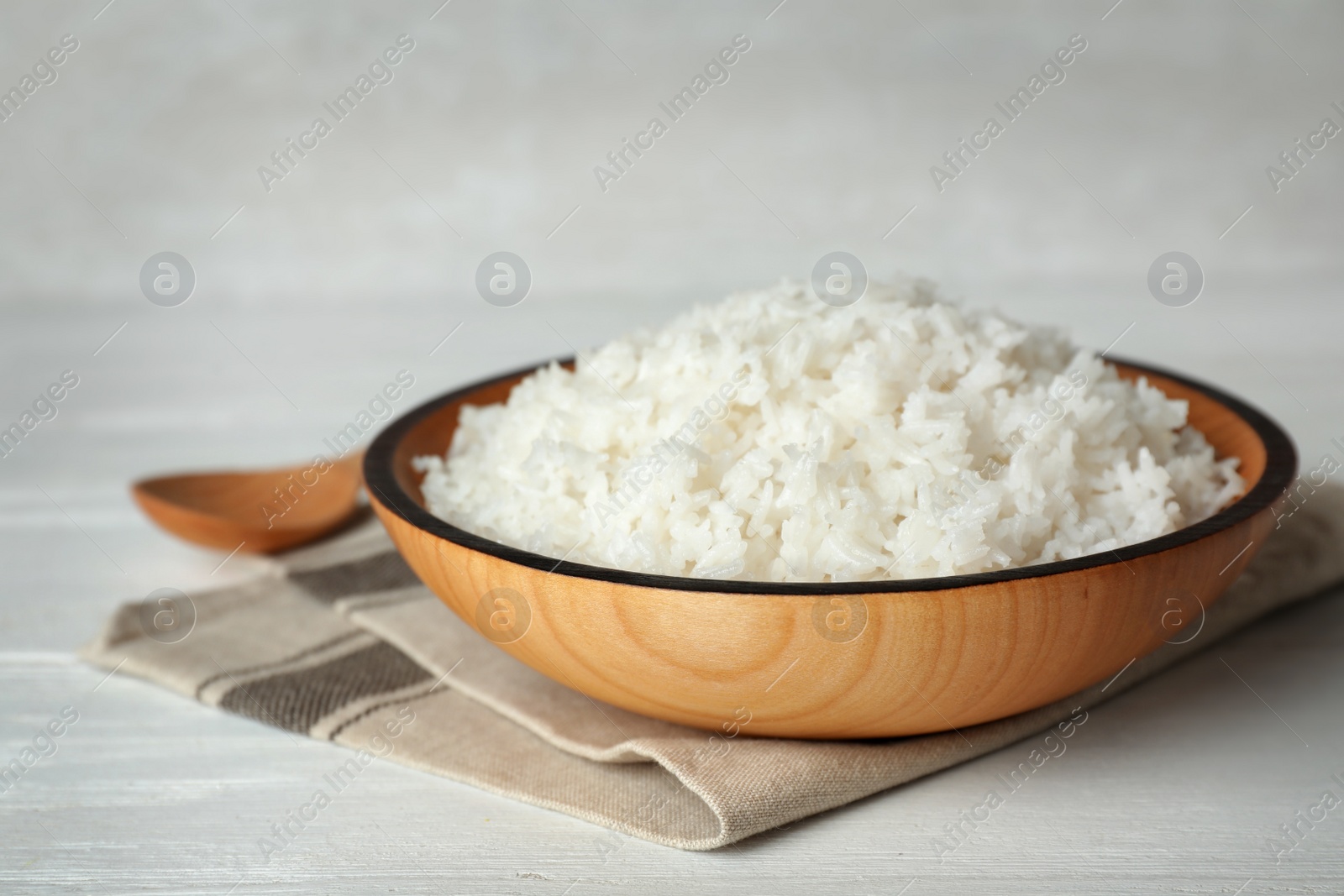 Photo of Bowl of boiled rice and spoon on wooden table