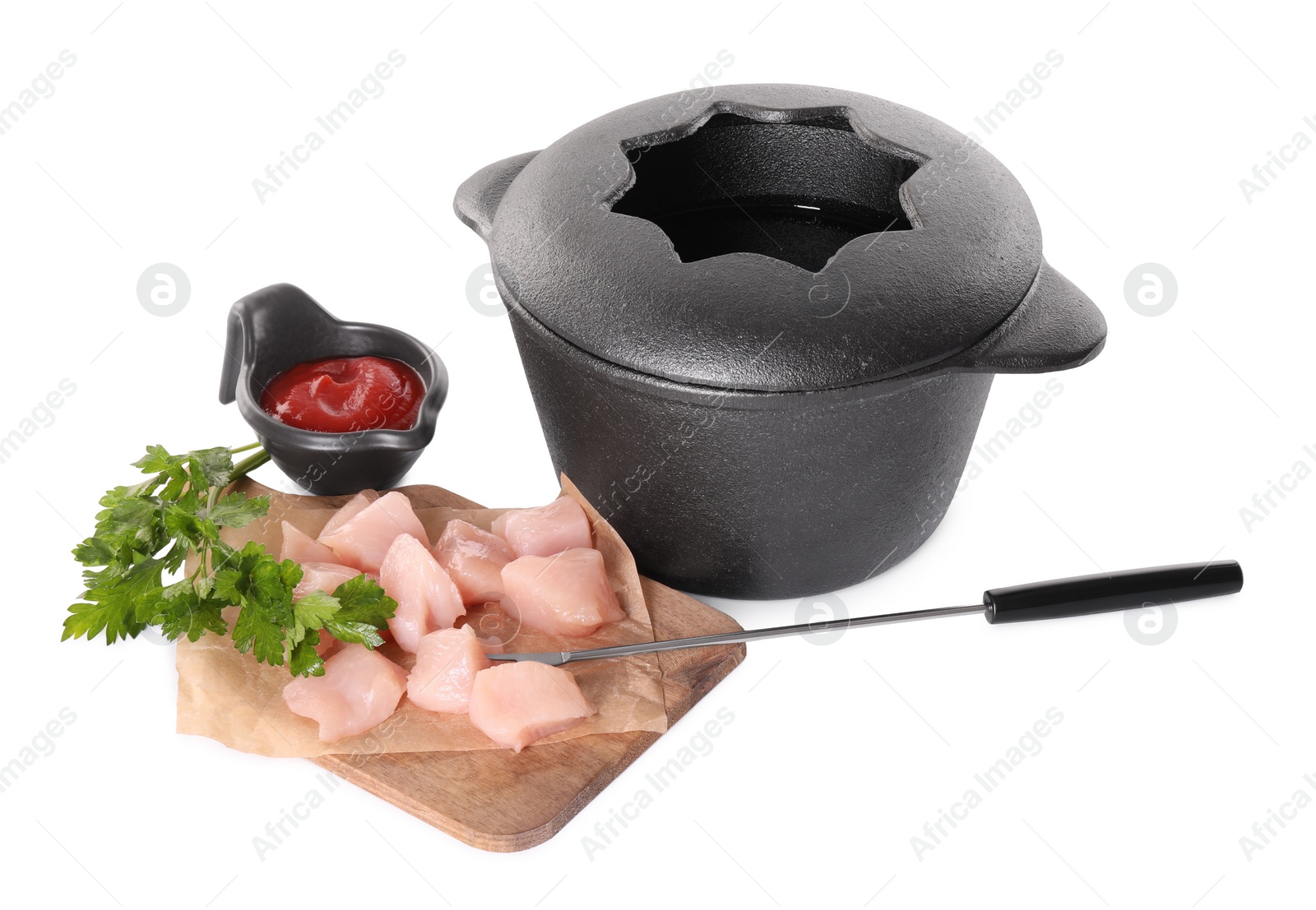 Photo of Fondue pot with oil, fork, raw meat pieces, sauce and parsley isolated on white