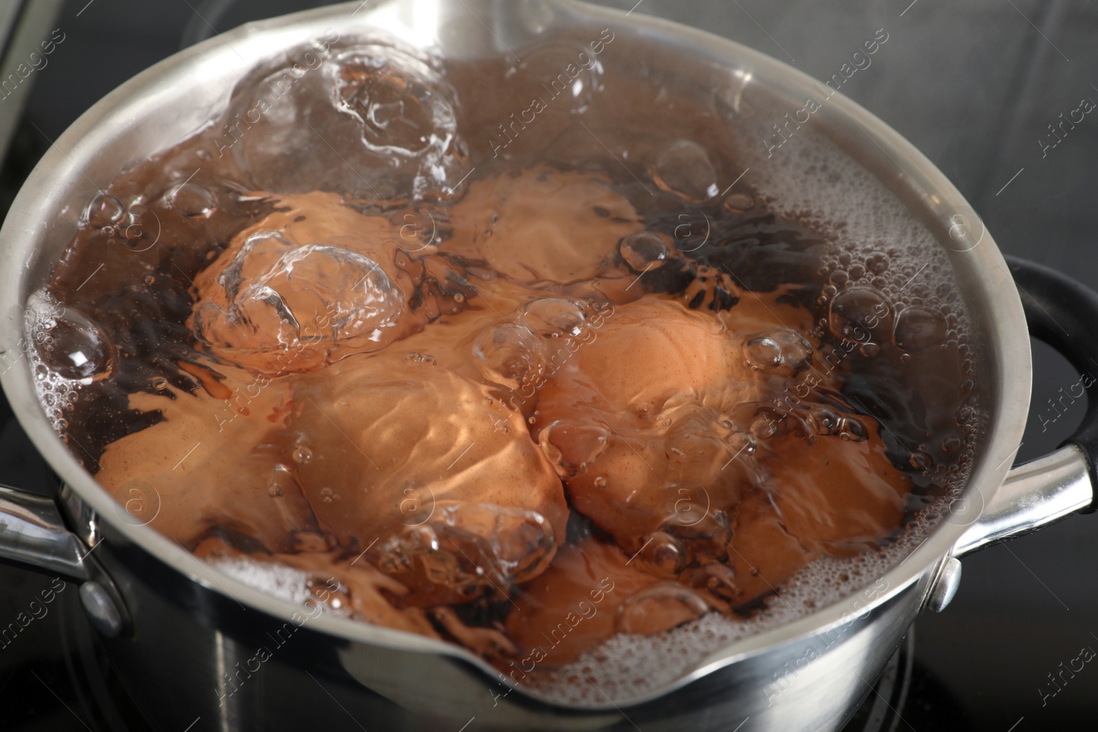 Photo of Cooking chicken eggs in pot on electric stove, closeup view