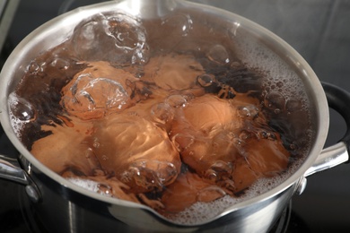 Cooking chicken eggs in pot on electric stove, closeup view