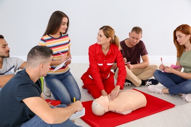 Instructor demonstrating CPR on mannequin at first aid class indoors
