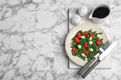 Photo of Tasty green beans with cheese and tomatoes served for dinner on marble table, top view