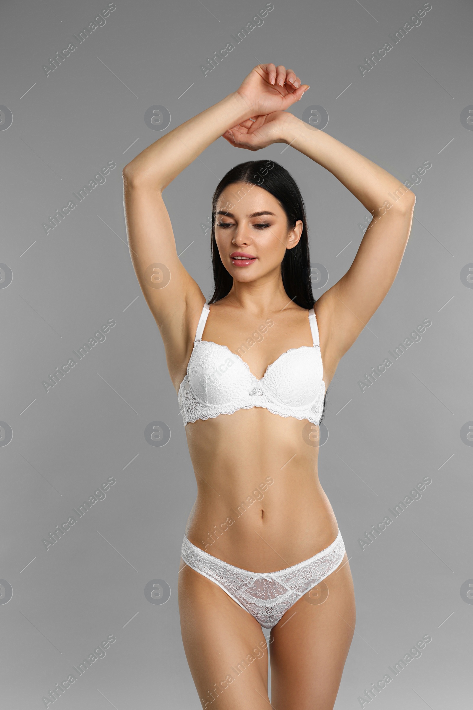 Photo of Beautiful young woman in white underwear on grey background