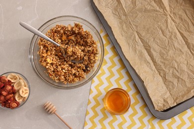 Photo of Making granola. Baking tray and ingredients on light grey marble table, flat lay