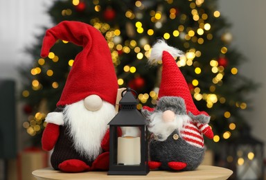 Photo of Funny Christmas gnomes and candle holder on coffee table in room with festive decoration