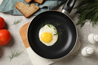 Delicious fried egg served with bread and tomatoes on grey table, flat lay