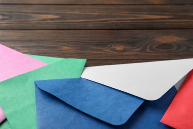 Colorful paper envelopes on wooden background, closeup