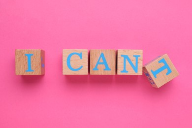 Photo of Motivation concept. Changing phrase from I Can't into I Can by removing wooden cube with letter T on pink background, top view
