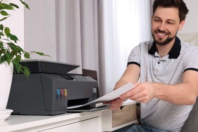 Man using modern printer at workplace indoors, selective focus