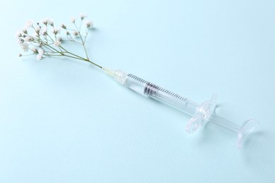 Cosmetology. Medical syringe and gypsophila on light blue background