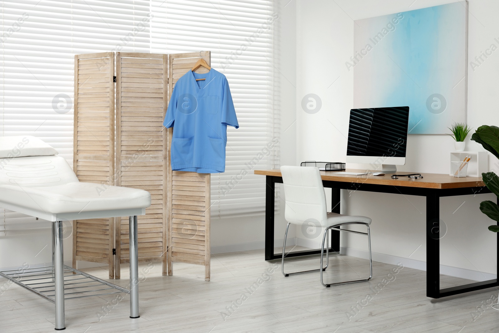 Photo of Modern medical office with doctor's workplace and examination table in clinic