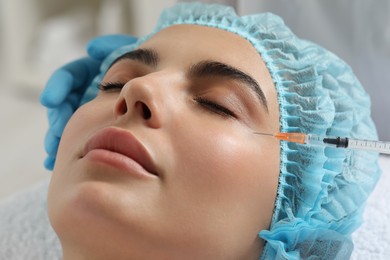 Doctor giving facial injection to young woman in clinic, closeup. Cosmetic surgery