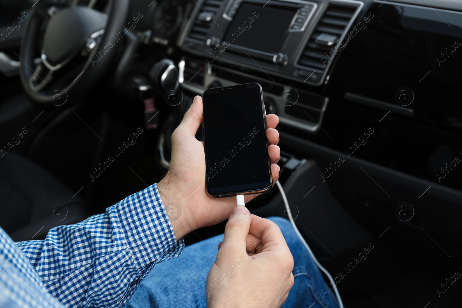 Photo of Man charging phone with USB cable in car