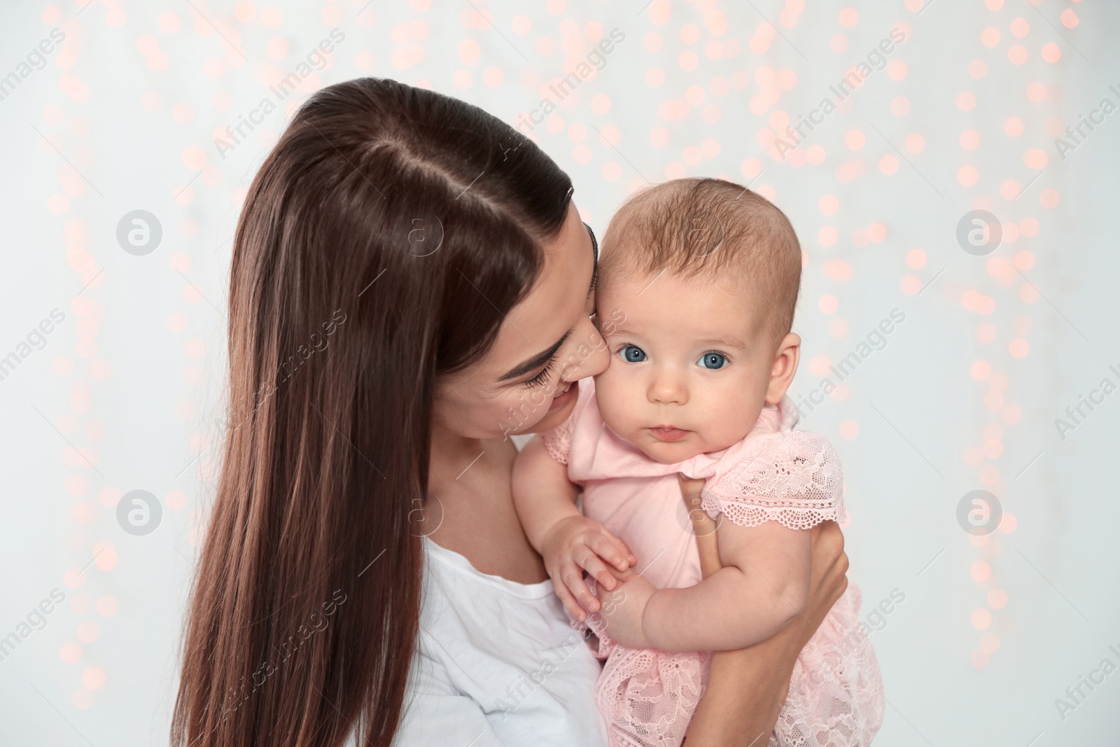 Photo of Portrait of happy mother with her baby against blurred lights