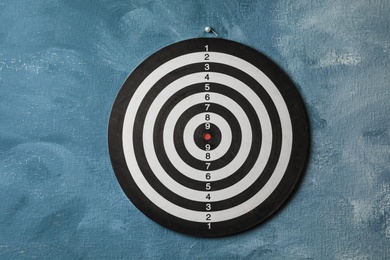 Photo of Dart board hanging on blue textured wall