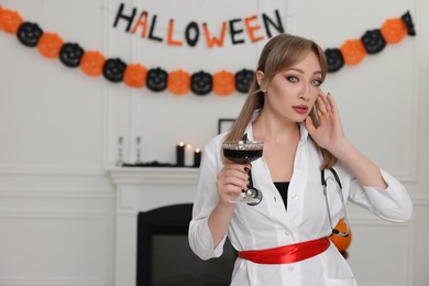 Woman in scary nurse costume with glass of wine indoors, space for text. Halloween celebration