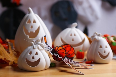 Photo of Composition with pumpkin shaped candle holders on wooden table, closeup. Halloween decoration