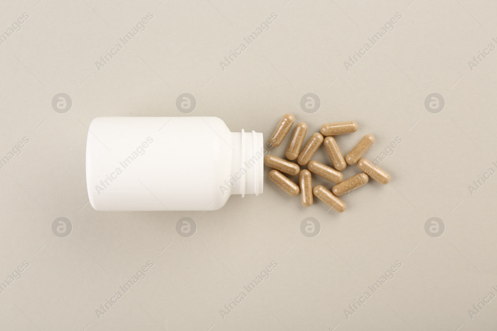 Photo of Bottle and vitamin capsules on light background, top view