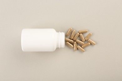 Photo of Bottle and vitamin capsules on light background, top view