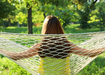 Young woman resting in comfortable hammock at green garden