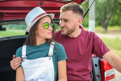 Photo of Beautiful young couple sitting in car trunk