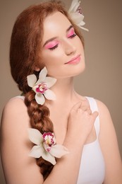 Portrait of beautiful young woman posing with lilies on beige background