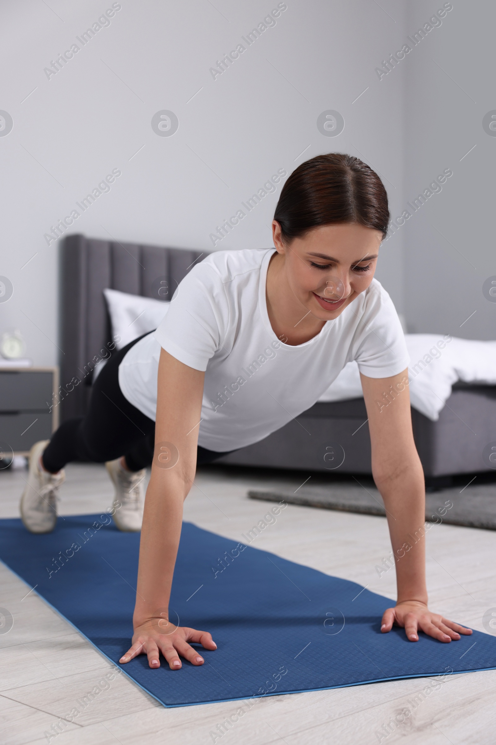 Photo of Happy woman doing plank exercise at home. Morning routine