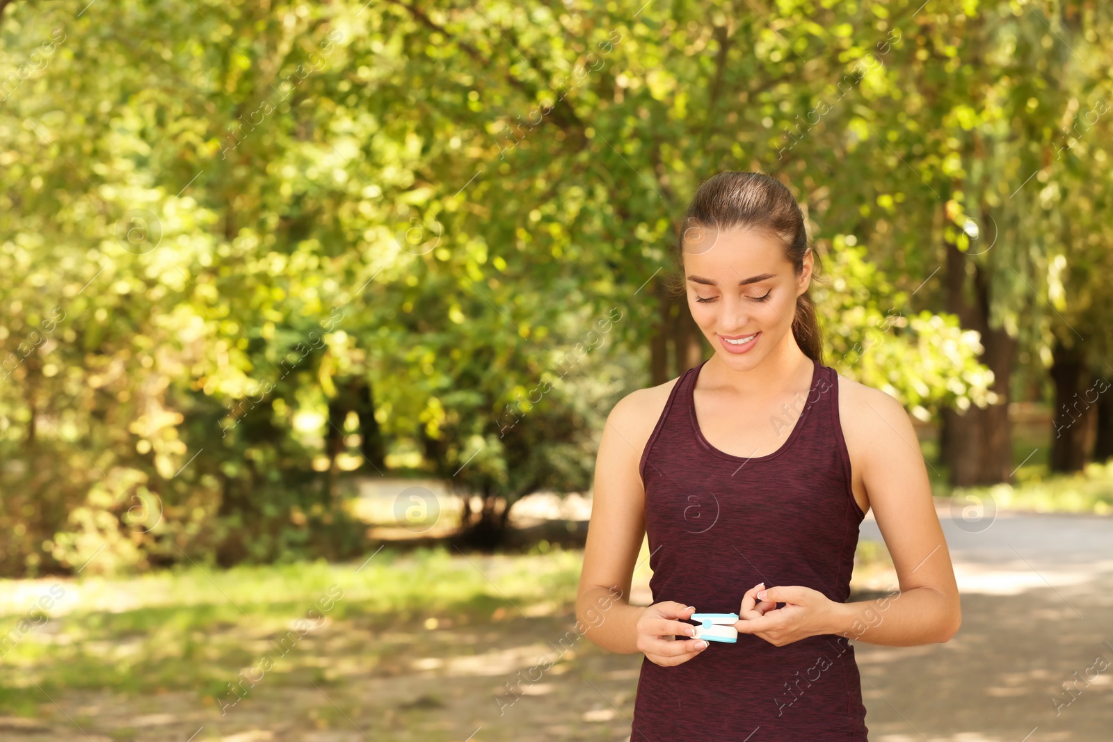 Photo of Young woman checking pulse outdoors on sunny day