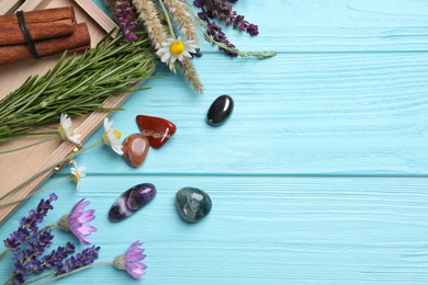 Photo of Gemstones and healing herbs on light blue wooden table, flat lay. Space for text
