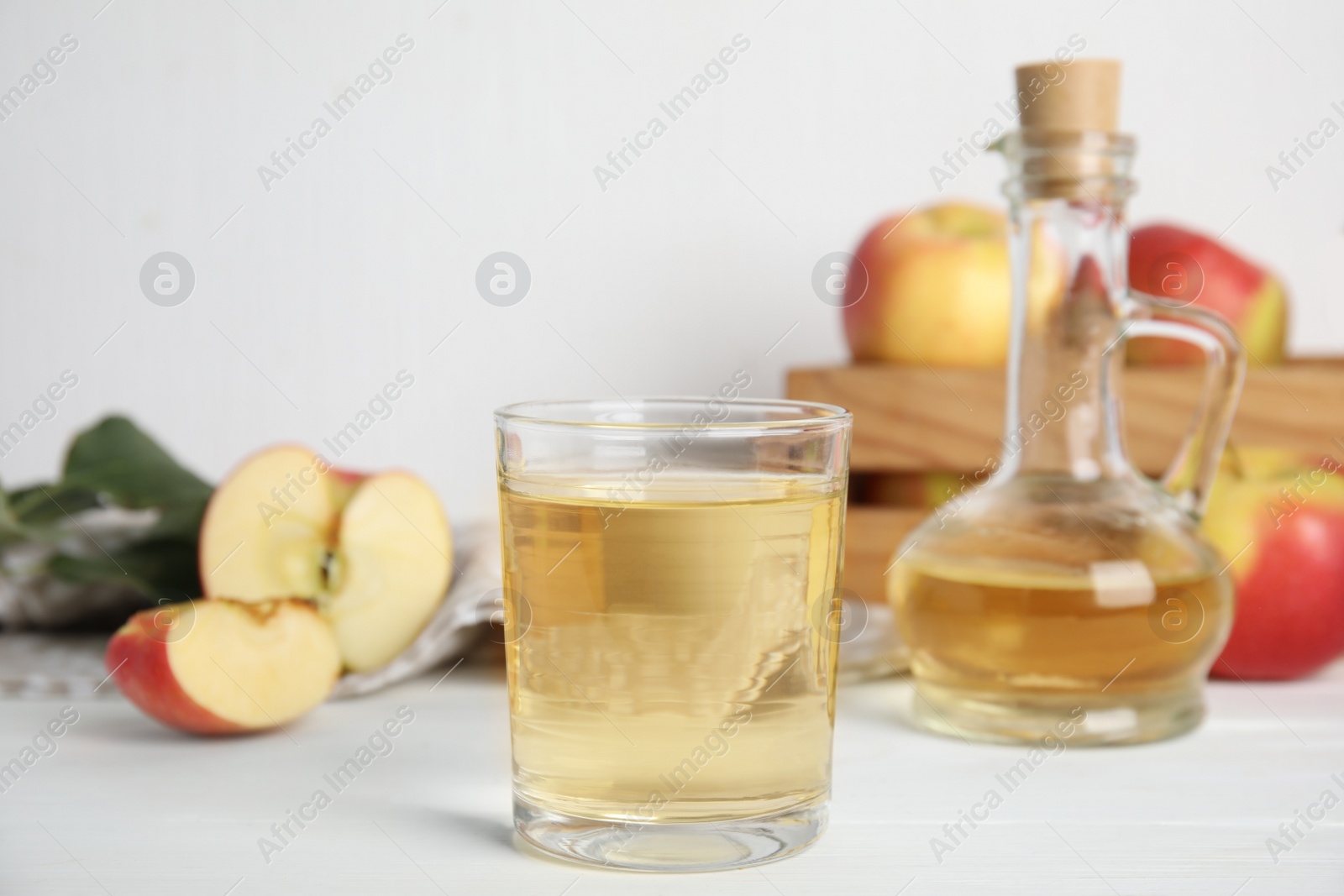 Photo of Natural apple vinegar and fresh fruits on white wooden table