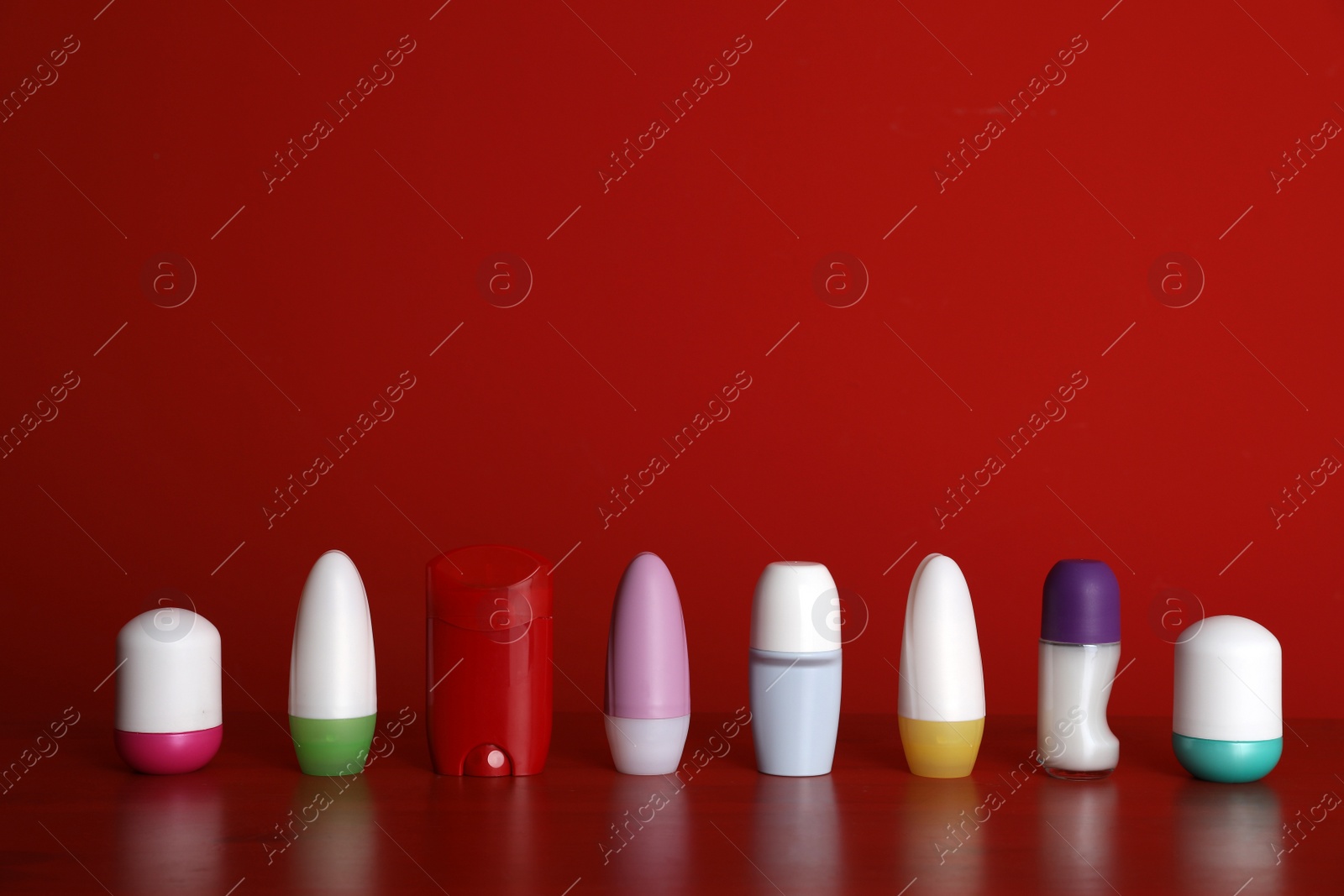 Photo of Different deodorants on table against red background. Space for design