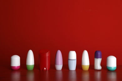 Different deodorants on table against red background. Space for design