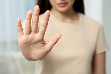 Photo of Woman showing stop gesture indoors, selective focus