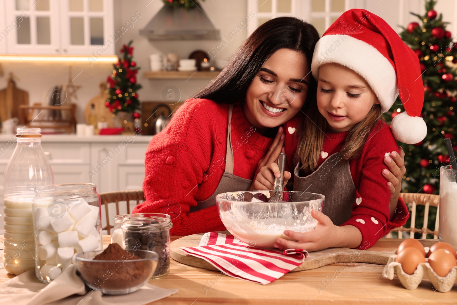 Photo of Happy mother and her daughter making dough for Christmas cookies at home