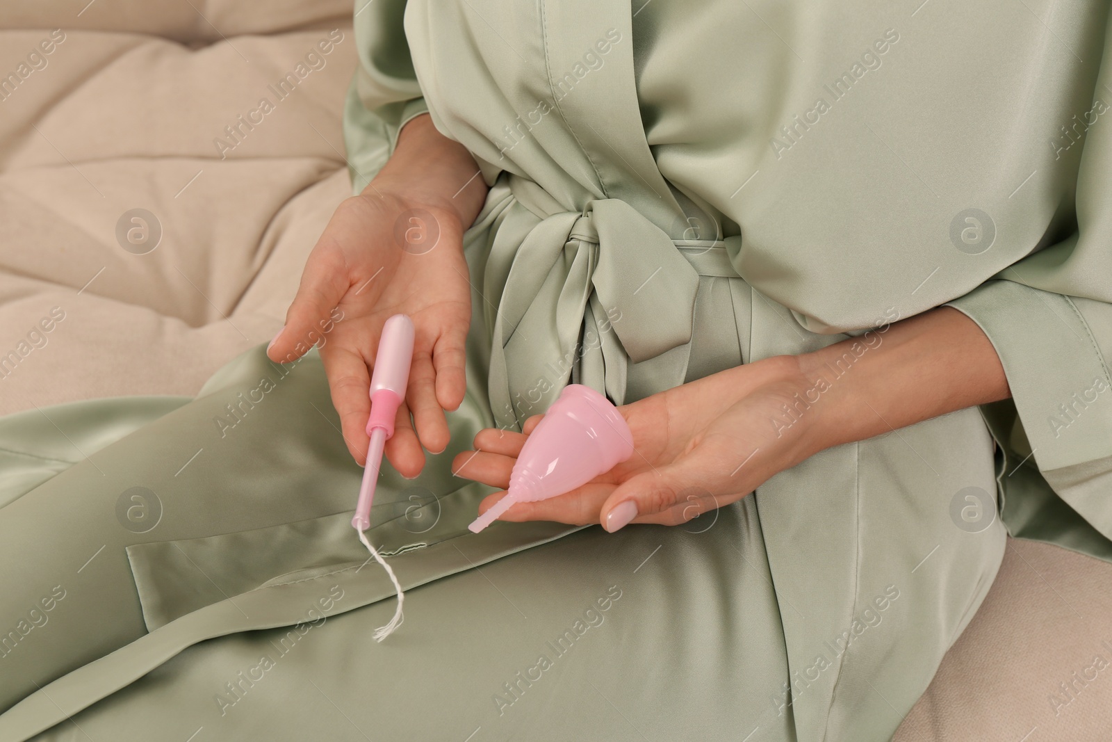 Photo of Young woman with menstrual cup and tampon on sofa, closeup