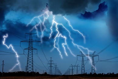 Image of Picturesque lightning storm over field with high voltage towers