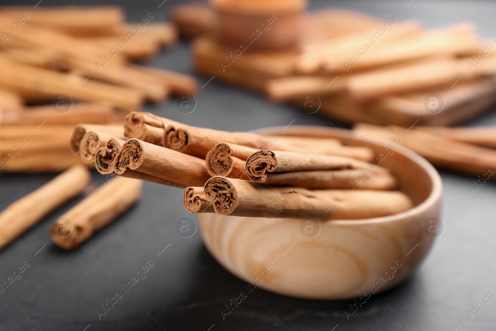 Photo of Aromatic cinnamon sticks on black table, closeup