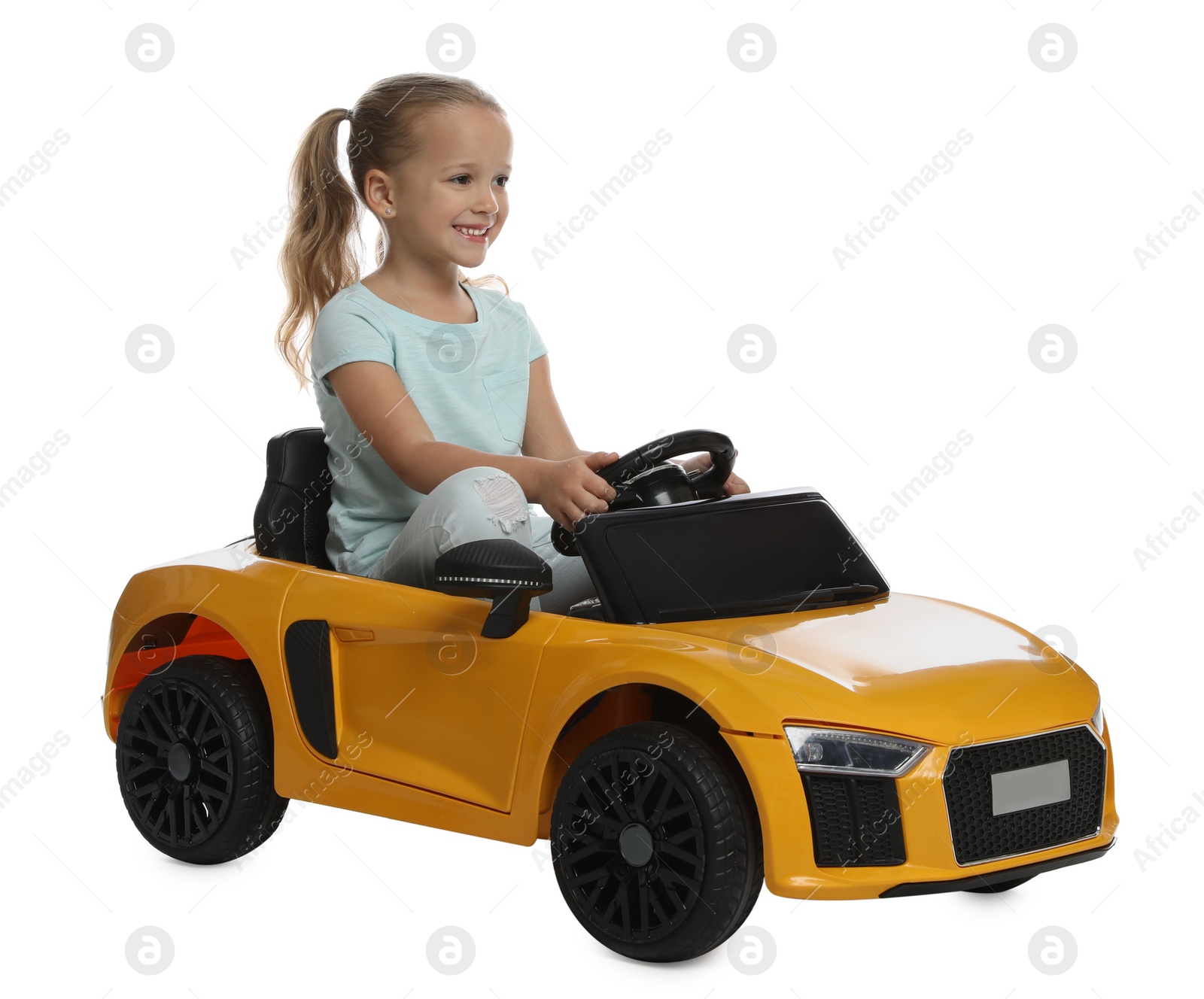 Photo of Cute little girl driving children's electric toy car on white background