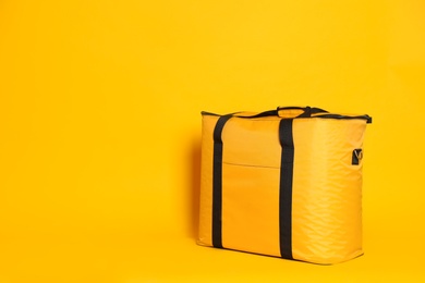 Photo of Modern thermo bag on yellow background. Space for text