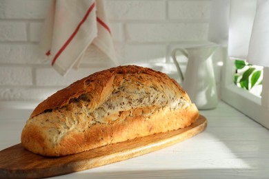 Freshly baked sourdough bread on white wooden table indoors