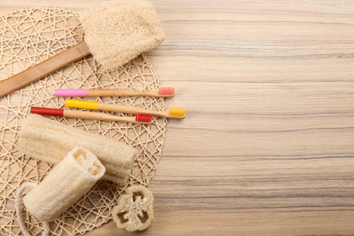 Photo of Flat lay composition with natural bamboo toothbrushes on wooden table, space for text