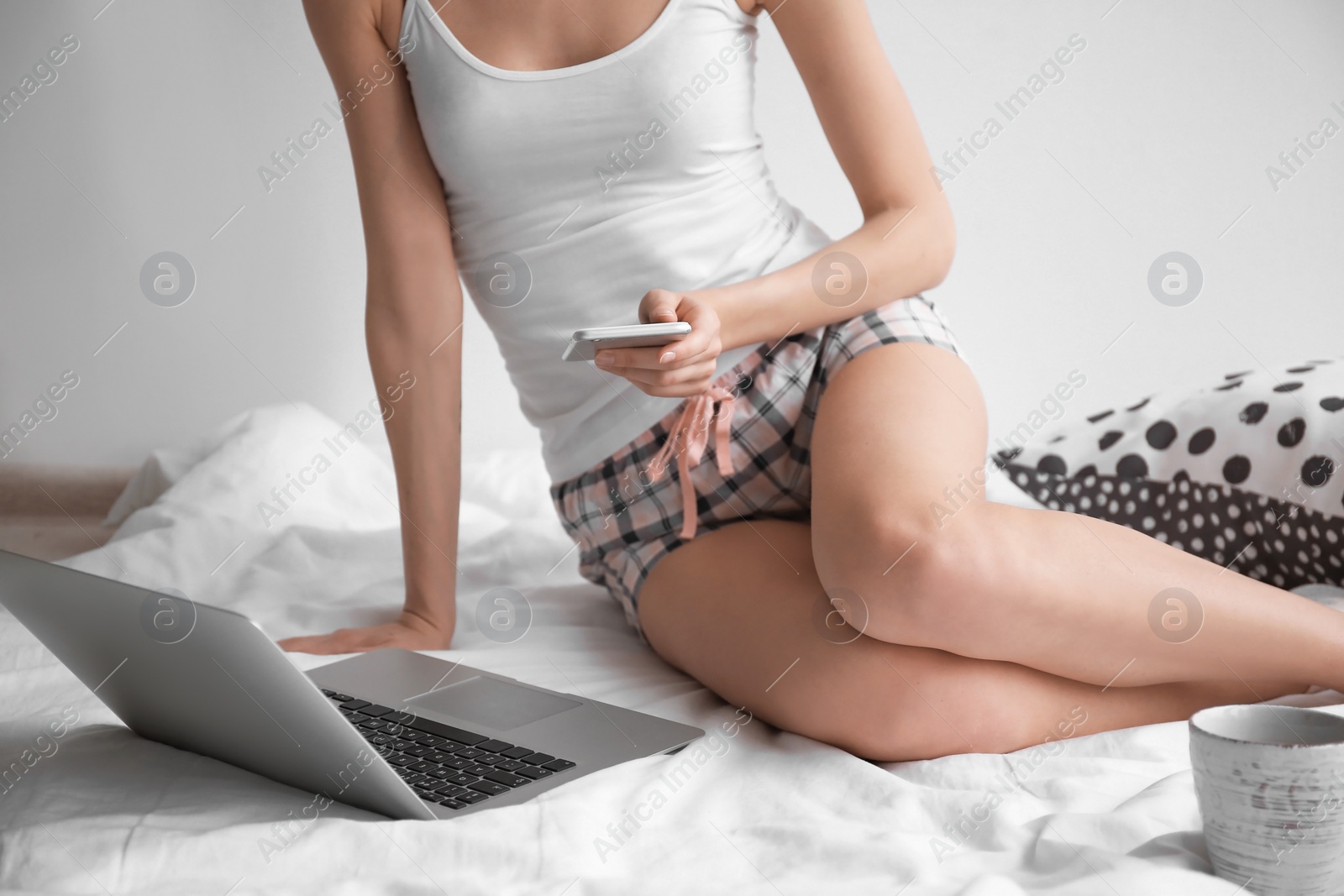 Photo of Female blogger with laptop and smartphone on bed