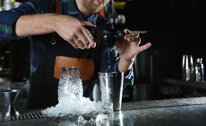 Barman making tropical cocktail at counter in pub, closeup. Space for text