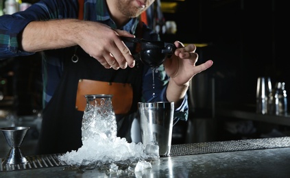 Photo of Barman making tropical cocktail at counter in pub, closeup. Space for text