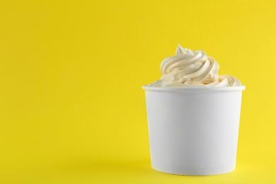 Cup with tasty frozen yogurt on yellow background. Space for text