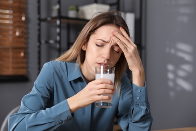 Woman taking medicine for hangover in office